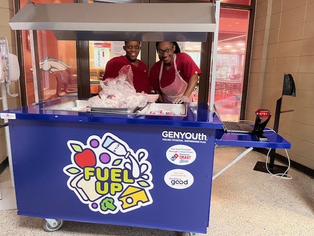 Two staff members stand with the new breakfast cart