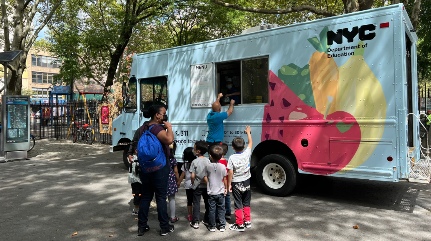 Children line up in front of a food truck to receive their summer meals