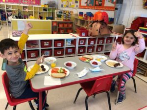 Two children eating a school meal with thumbs up