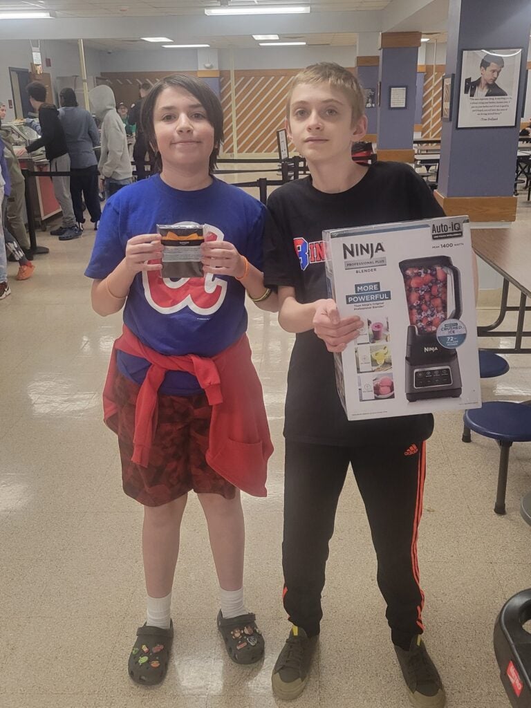 One student holds a giftcard while another holds a blender