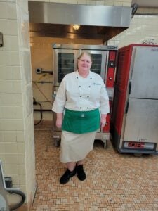 Ms. Dunn stands in the kitchen and smiles at the camera