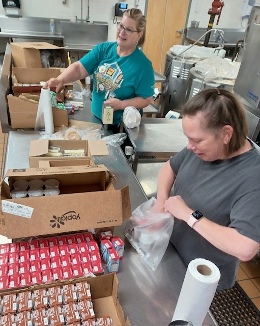 Two women pack meals in the kitchen