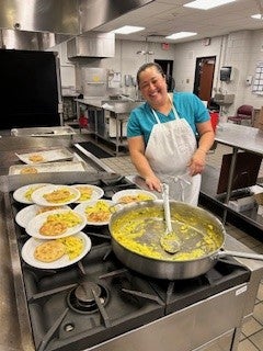 A food service worker smiles at camera inside the kitchen