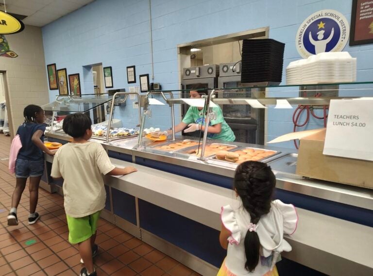 Students wait at the serving line while a cafeteria worker serves food